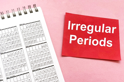 Red paper with ‘Irregular Periods’ text placed next to calendar on pink background